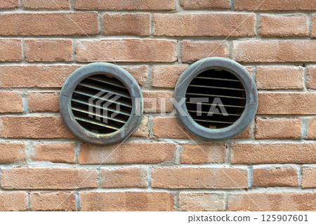 Two Round Vent Grilles in Brick Wall Two Round Vent Grilles in Brick Wall 125907601