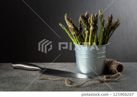 Fresh asparagus in small bucket on a gray background. Fresh asparagus in small bucket on a gray background. 125908287
