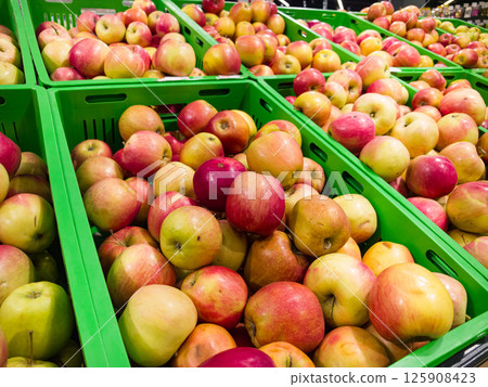 Bountiful harvest of fresh apples displayed in vibrant green crates 125908423