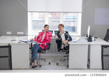 Colleagues communicate while at work in the office.  125908684