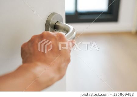 A woman holding the doorknob and preparing to enter a new home. Image of searching for a new home or moving to a new home. 125909498