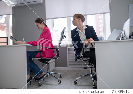Caucasian young man spying on colleague. Caucasian young man spying on colleague. 125909612