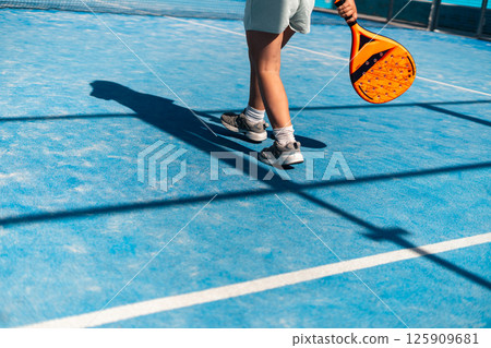 Sports action on a bright blue court with orange racket. Sports action on a bright blue court with orange racket. 125909681