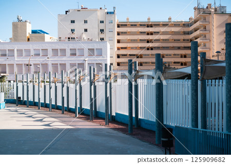 Urban architecture with modern fences and buildings under a clear sky. 125909682