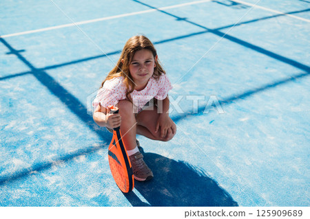 Young girl with paddle on blue sports court, ready to play. Young girl with paddle on blue sports court, ready to play. 125909689