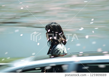 Woman walking through a dreamy blur of pink cherry blossom petals, soft spring atmosphere with falling flowers 125909889