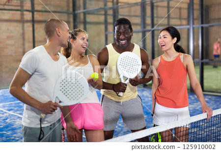 Cheerful team of men and women after playing padel on tennis court 125910002