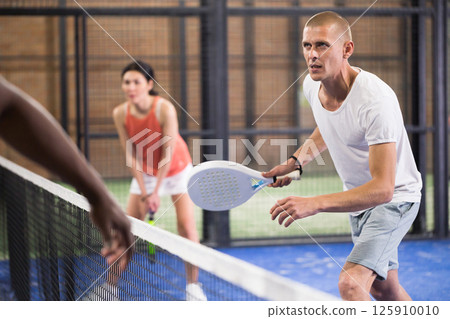 Male player ready to hits the ball while playing padel 125910010