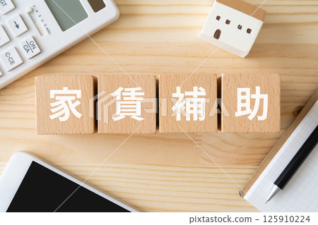 一塊寫有「租金援助」的方塊、一棟房屋模型和一台計算器 125910224