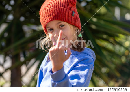 Portrait of girl in red knit cap making obscene 125910239