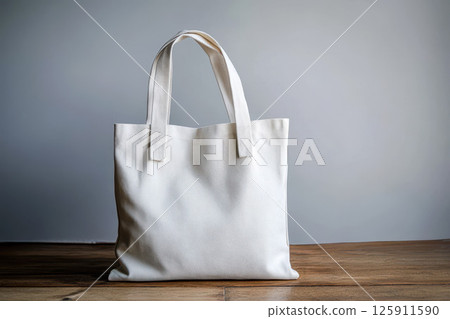 White tote bag on wood floor with shadows. 125911590