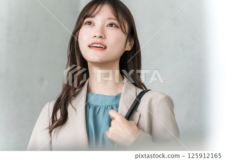 Smiling young Asian businesswoman looking up Smiling young Asian businesswoman looking up 125912165