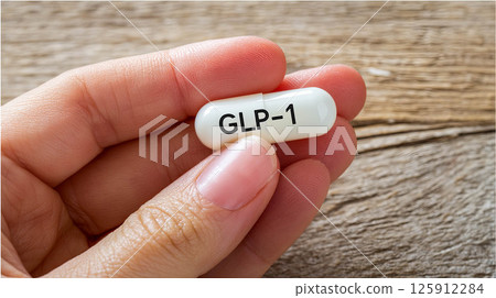 GLP-1 medication capsule held in hand representing modern health solutions and wellness concept 125912284