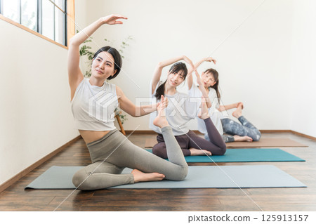 在瑜伽館和瑜伽課（體育館）中練習瑜伽和普拉提的女性 125913157