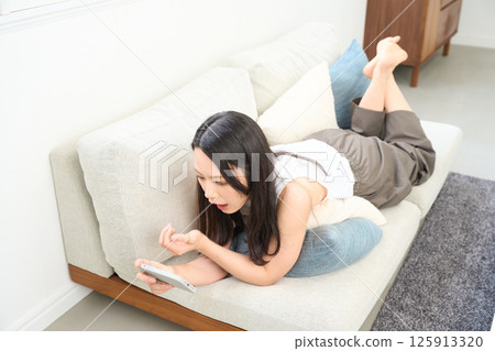 Woman looking at smartphone while lying down. Surprised. Surprised. 125913320
