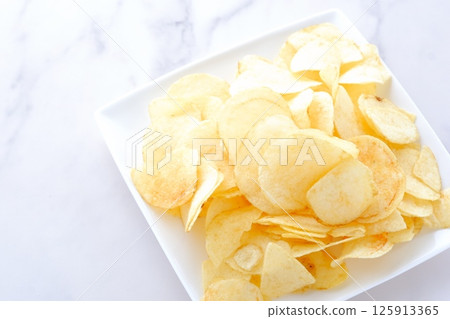 A pile of potato chips on a white plate 125913365