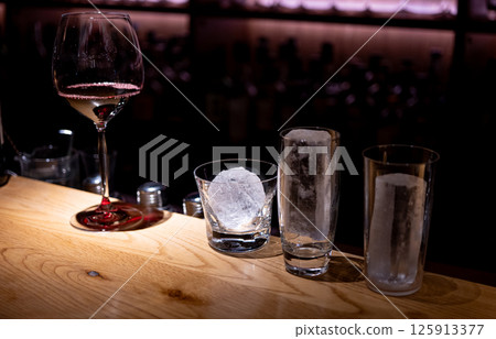 Red wine poured into a glass, round ice, long glass Red wine poured into a glass, round ice, long glass 125913377