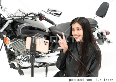 一位摩托車部落客在智慧型手機相機前做出和平手勢 125913536