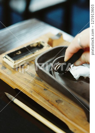 Close-up of hands preparing ink for calligraphy, a traditional Japanese culture 125913603