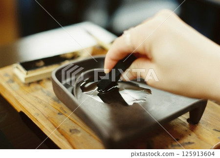 Close-up of hands preparing ink for calligraphy, a traditional Japanese culture 125913604