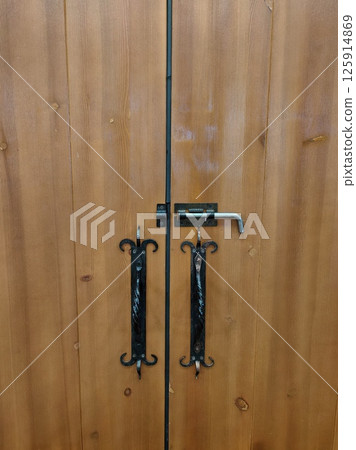 decorative wooden doors with ornate handles and lock in rustic setting. close-up. decorative wooden doors with ornate handles and lock in rustic setting. close-up. 125914869