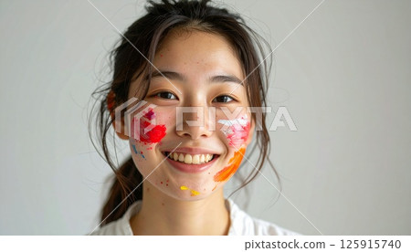 portrait of a smiling young woman with painted face, a cheerful young woman with colorful paint on her face, natural lighting, and bright smile, Perfect for themes of joy, creativity, youth, beauty 125915740