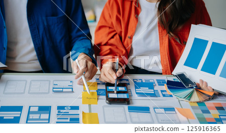 UX developer and ui designer brainstorming about mobile app interface wireframe design with customer breif and color code at modern office. UX developer and ui designer brainstorming about mobile app interface wireframe design with customer breif and color code at modern office. 125916365