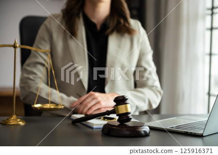 justice and law concept.law theme  wooden desk, books, balance. Male judge in a courtroom the gavel,working with digital tablet computer on table 125916371