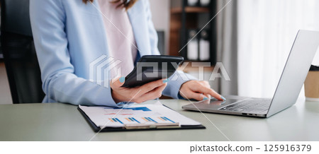 Hand business doing finances and calculate on desk about cost using on smartphone and tablet as concept 125916379