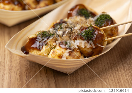 Takoyaki being pierced with a bamboo skewer and lifted up 125916614