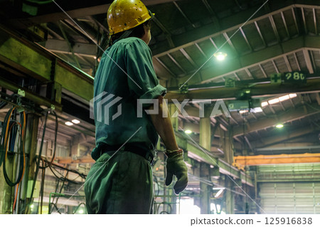 Rear view of a man in work clothes and a factory 125916838