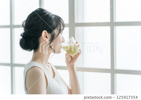 Young asian woman drinking a green smoothie at home 125917354