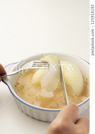 Lifting the onion from the stewed new onion soup with a fork 125918192