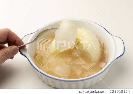 用叉子將洋蔥從燉好的新洋蔥湯中取出 125918194