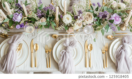 Elegant wedding table with floral centerpiece, gold accents and purple lavender details 125918405