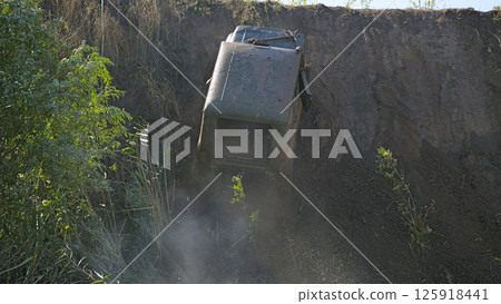 Dramatic view of an off-road vehicle climbing a steep cliff. The vehicle is tilted at a dangerous angle. Extreme off-road racing 125918441
