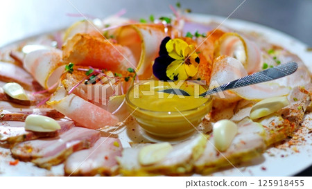 mint plates of white and black color with boiled pork, slices of lard, herbs with a bottle of cognac, a buffet, with mustard and red sauce on a table with a beautiful tablecloth. 125918455