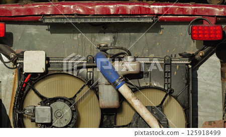 Close-up of the cooling system of a car. Radiator with pipes, fan and electronic components. Mounted on the rear of the SUV. Use in rough terrain Close-up of the cooling system of a car. Radiator with pipes, fan and electronic components. Mounted on the rear of the SUV. Use in rough terrain 125918499