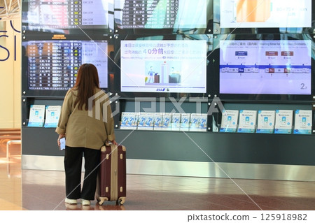 Woman checking departing flights, travelers at Haneda Airport, woman looking at flight schedule 125918982