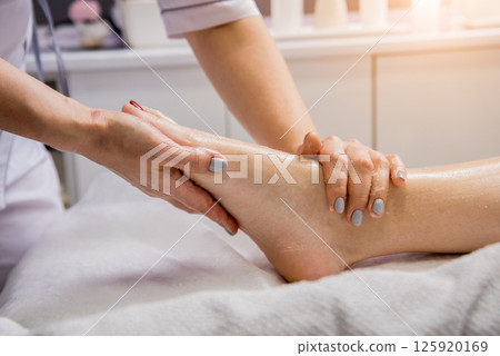 Beautiful young woman enjoying foot massage in spa salon. Cosmetology Beautiful young woman enjoying foot massage in spa salon. Cosmetology 125920169