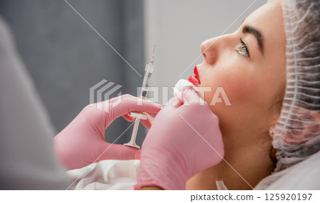 The doctor cosmetologist makes the facial injections procedure. The doctor cosmetologist makes the facial injections procedure. 125920197