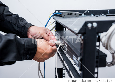 Technician connecting network cables to switches. Connecting cables Technician connecting network cables to switches. Connecting cables 125920198