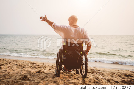 Disabled man in a wheelchair on the beach. Disabled man in a wheelchair on the beach. 125920227