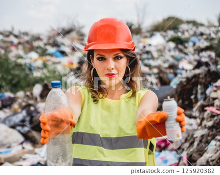 Woman volunteer helps clean the field of plastic garbage.  125920382