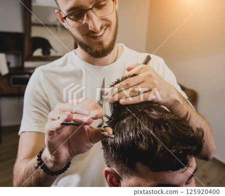 Young man with trendy haircut at barber shop.  125920400