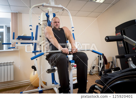 Disabled man doing strength exercises separate from the wheelchair. 125920401
