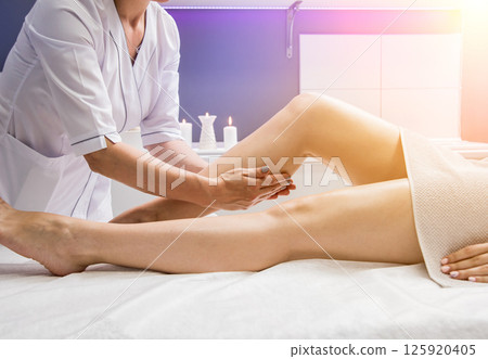 Beautiful young woman enjoying legs massage with oil in spa salon. Cosmetology Beautiful young woman enjoying legs massage with oil in spa salon. Cosmetology 125920405