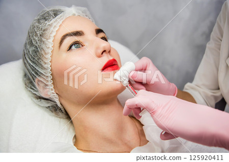 The doctor cosmetologist makes the facial injections procedure. The doctor cosmetologist makes the facial injections procedure. 125920411