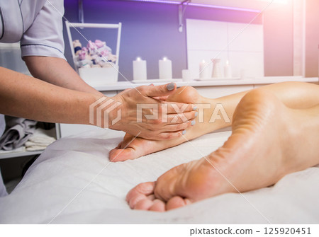 Beautiful young woman enjoying foot massage in spa salon. Cosmetology 125920451