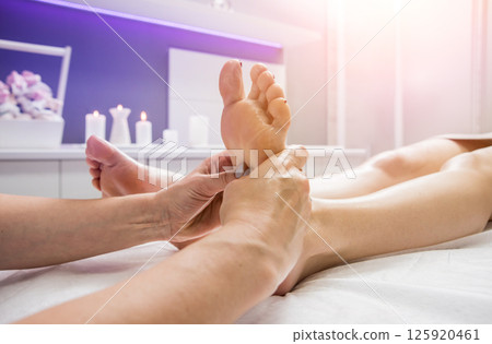 Beautiful young woman enjoying foot massage in spa salon. Cosmetology 125920461